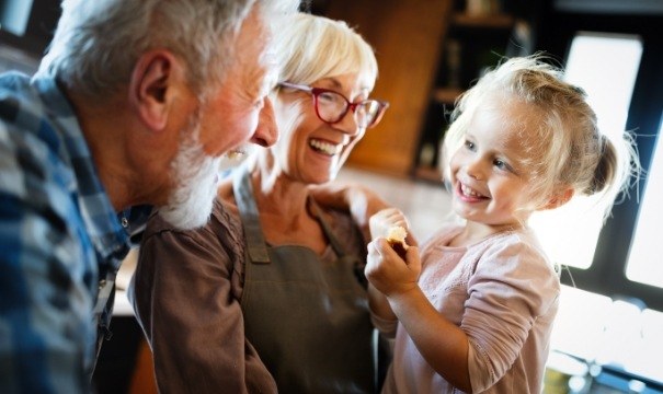 Grandparents smiling at grandchild enjoying the benefits of dental implants