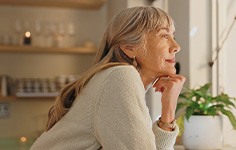 Senior woman smiling while looking out the window at home