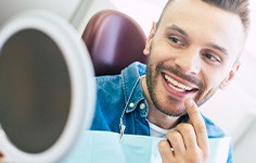 Man smiling at reflection in handheld mirror