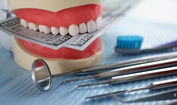 Dental model biting down on paper money