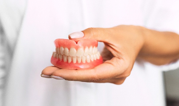 Dentist holding full dentures in Boston