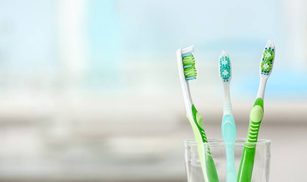 Three toothbrushes in a clear cup
