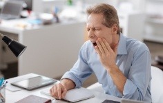 Man with jaw pain holding his cheek