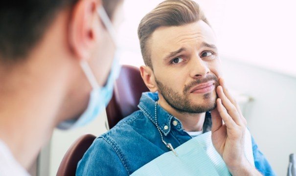 Man in need of root canal therapy holding jaw in pain