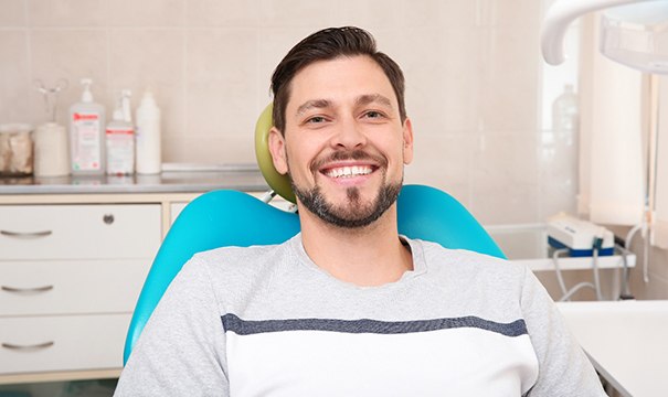 Male dental patient sitting in chair and smiling