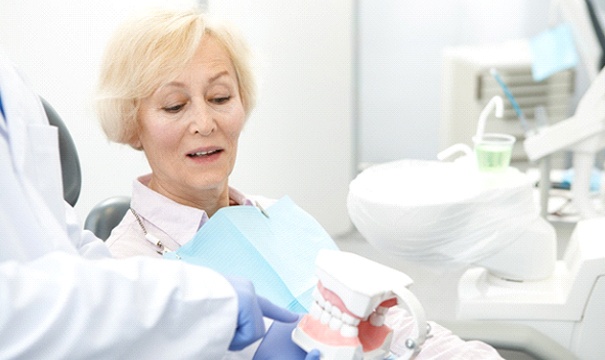 dentist showing a denture to a patient