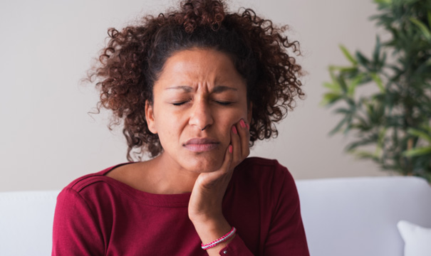 Woman wincing in pain and holding the side of her face