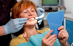 patient smiling while looking in dental mirror 
