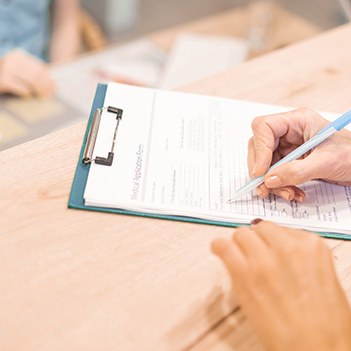 Person filling out paperwork on clipboard