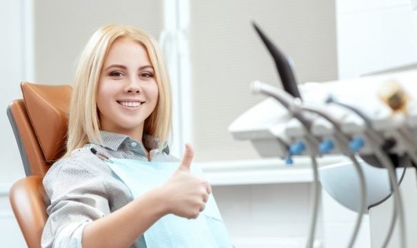 Woman in dental chair giving thumbs up