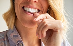 a woman putting Invisalign aligners in her mouth
