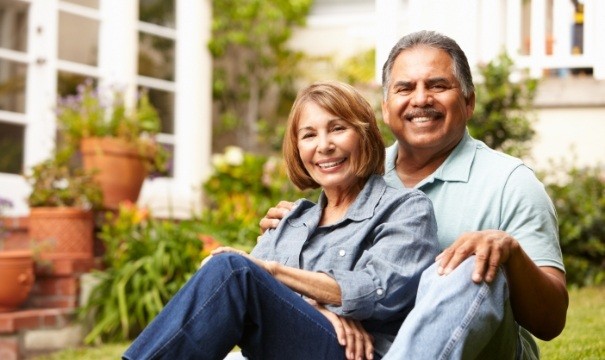 Man and woman smiling after replacing missing teeth with dental bridges