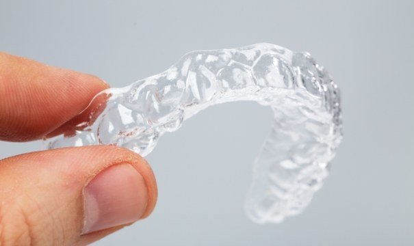 Hand holding an Invisalign clear aligner