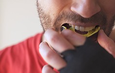 A young man putting a mouthguard in his mouth