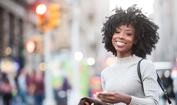 Woman walking on the street smiling with veneers in Boston, MA