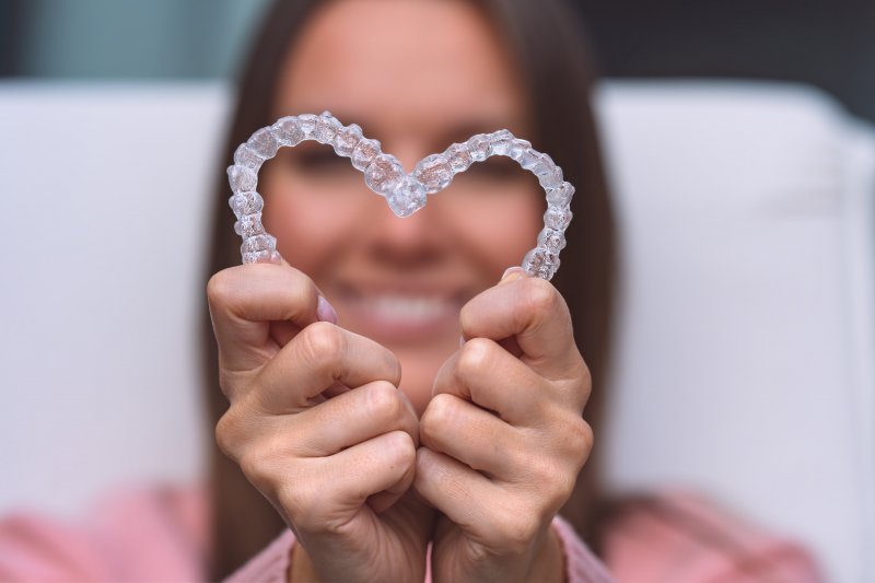 Woman holding Invisalign aligners in the shape of heart