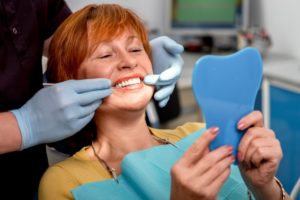 a woman at the dentist smiling after her dental implant surgery