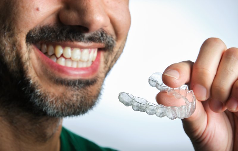 Man holding up one of his mail-in clear aligners