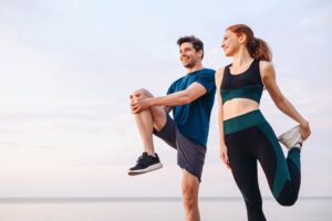 Man and woman in exercise clothes outside stretching before a run